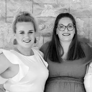 Black and white image of Jac & Candice WIBALSA CoFounders smiling against a brick background - Photo by Captured By Shemieke